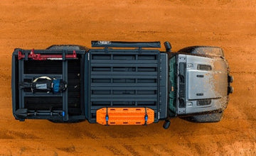 Top-down view of a truck bed with storage compartments on a wooden surface