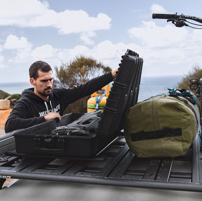 Man loading a bike onto a roof rack with a scenic background