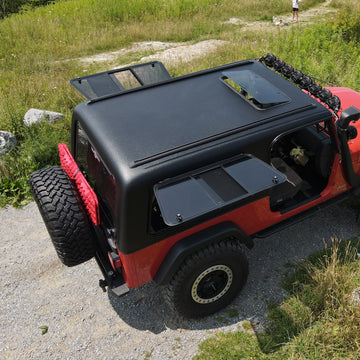 Red off-road vehicle with black roof rack on a rocky path