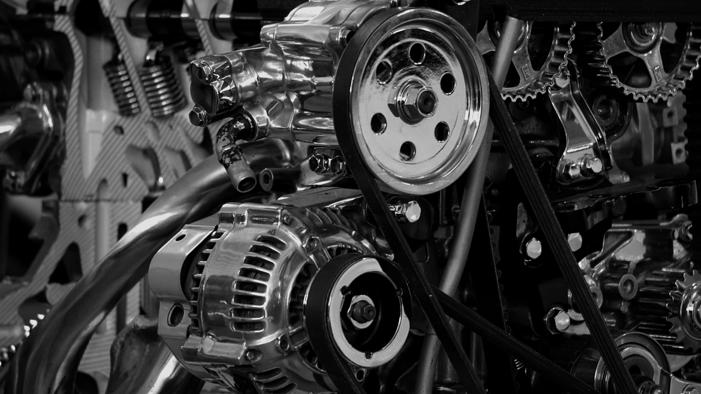 Close-up of a mechanical engine with gears and belts in black and white.