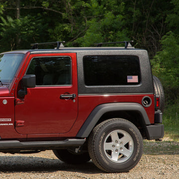 Red Jeep Wrangler parked on a gravel road with trees in the background