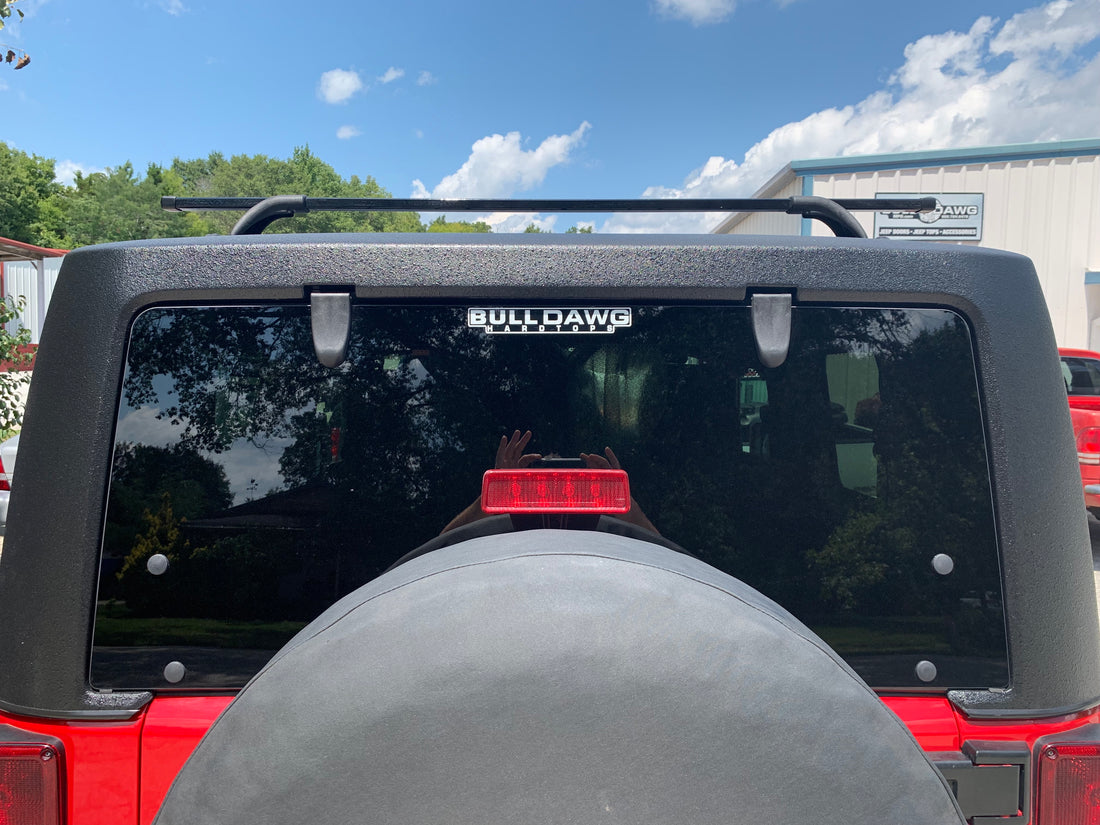 Gray Jeep Wrangler Rubicon parked on a gravel road with greenery in the background