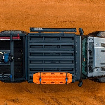 Top-down view of a truck bed with storage compartments on a wooden surface