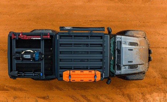 Top-down view of a truck bed with storage compartments on a wooden surface