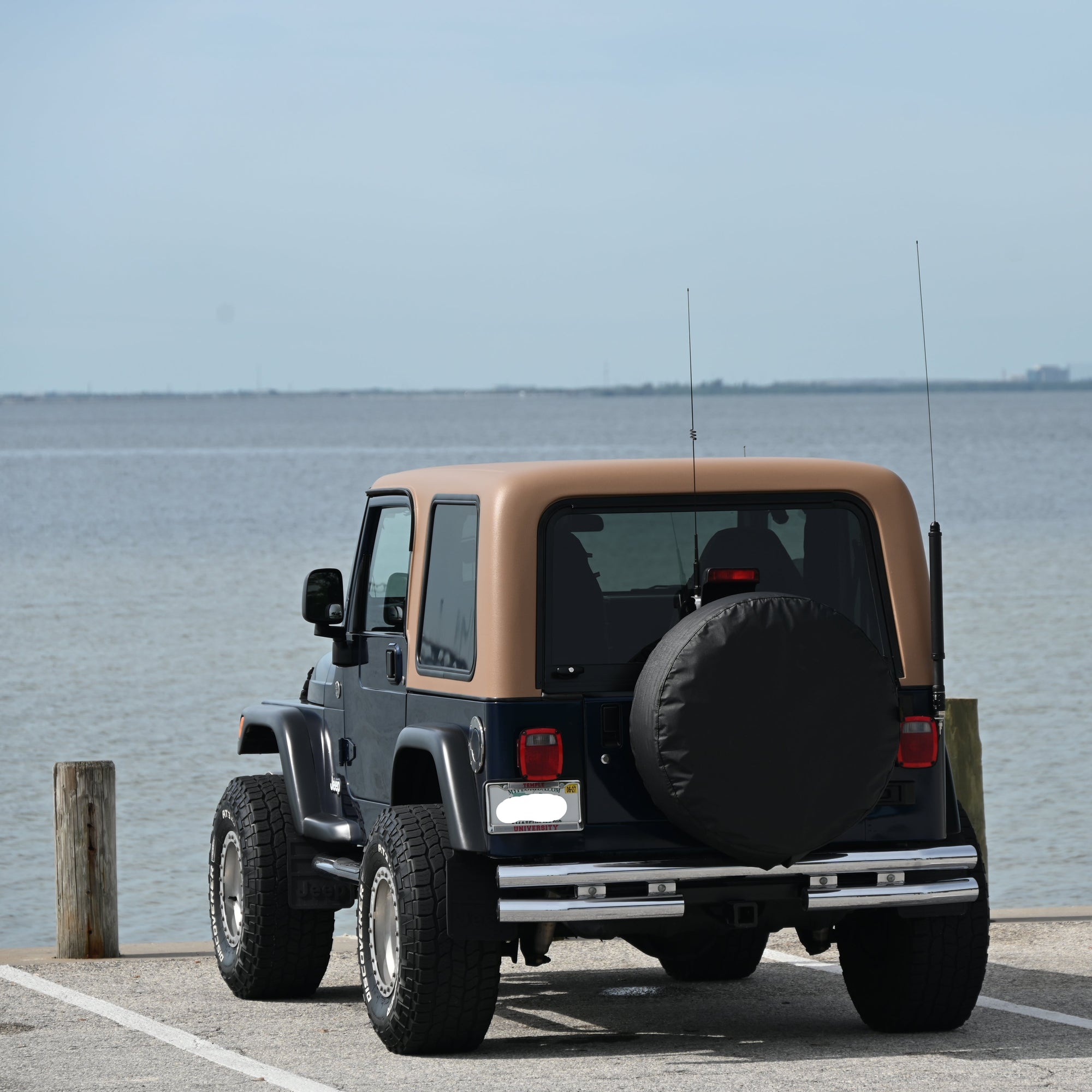 Jeep parked by a body of water with a clear sky