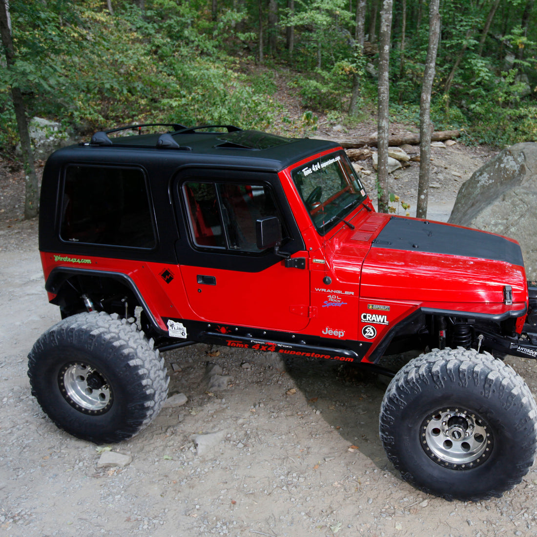 Red off-road vehicle on a dirt path with trees in the background