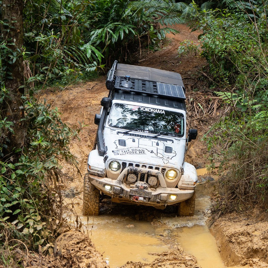 Off-road vehicle navigating a muddy trail in a forest