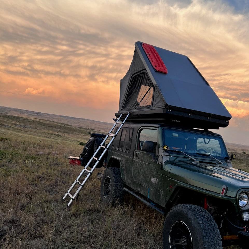 Red off-road Jeep with black roof rack on a rocky path