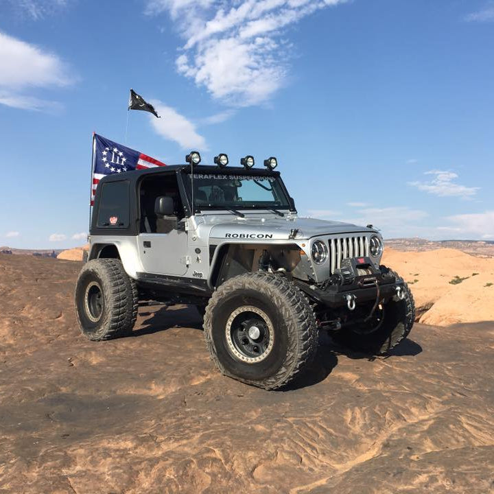 Jeep Wrangler with 'Liberty' flag in a desert landscape